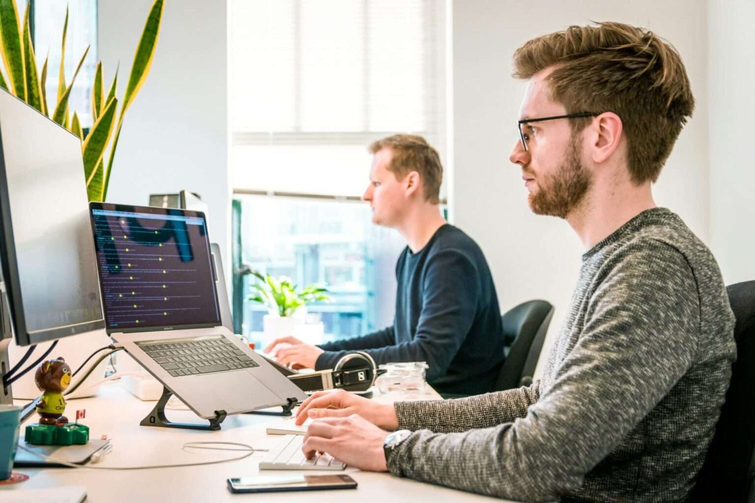 Zwei Männer arbeiten im Büro an Computern.