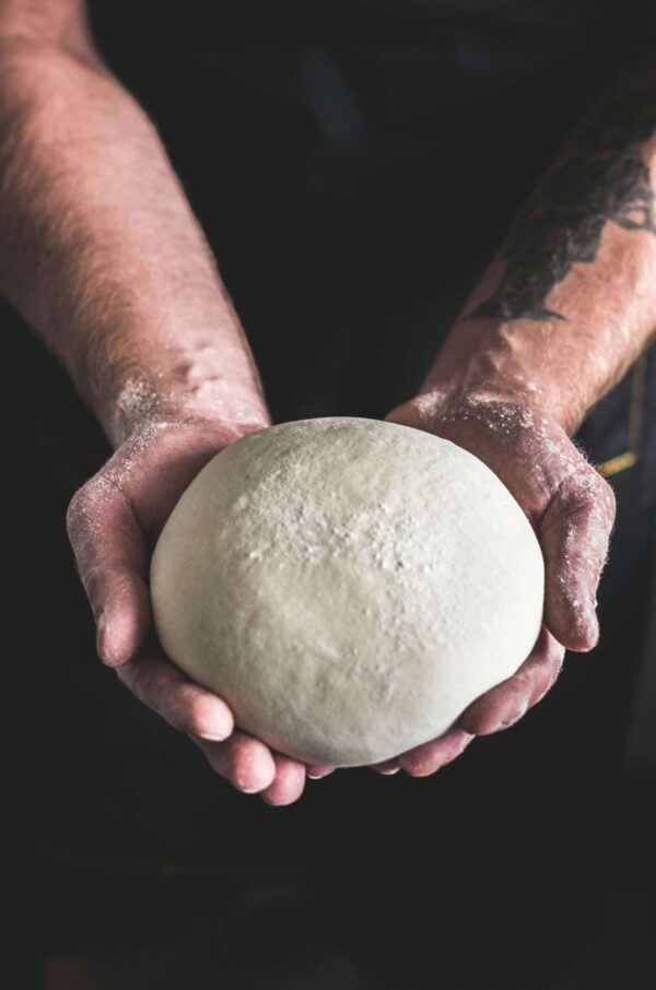 Hände formen Teigball zum Backen.