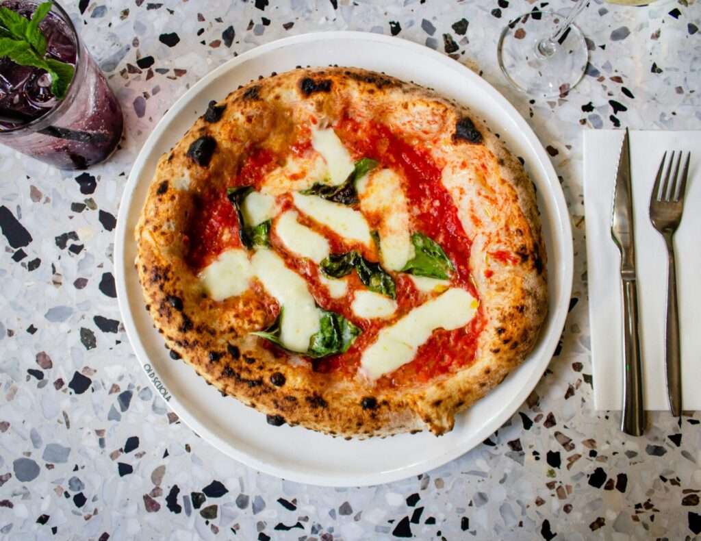 Margherita Pizza auf Teller mit Getränk